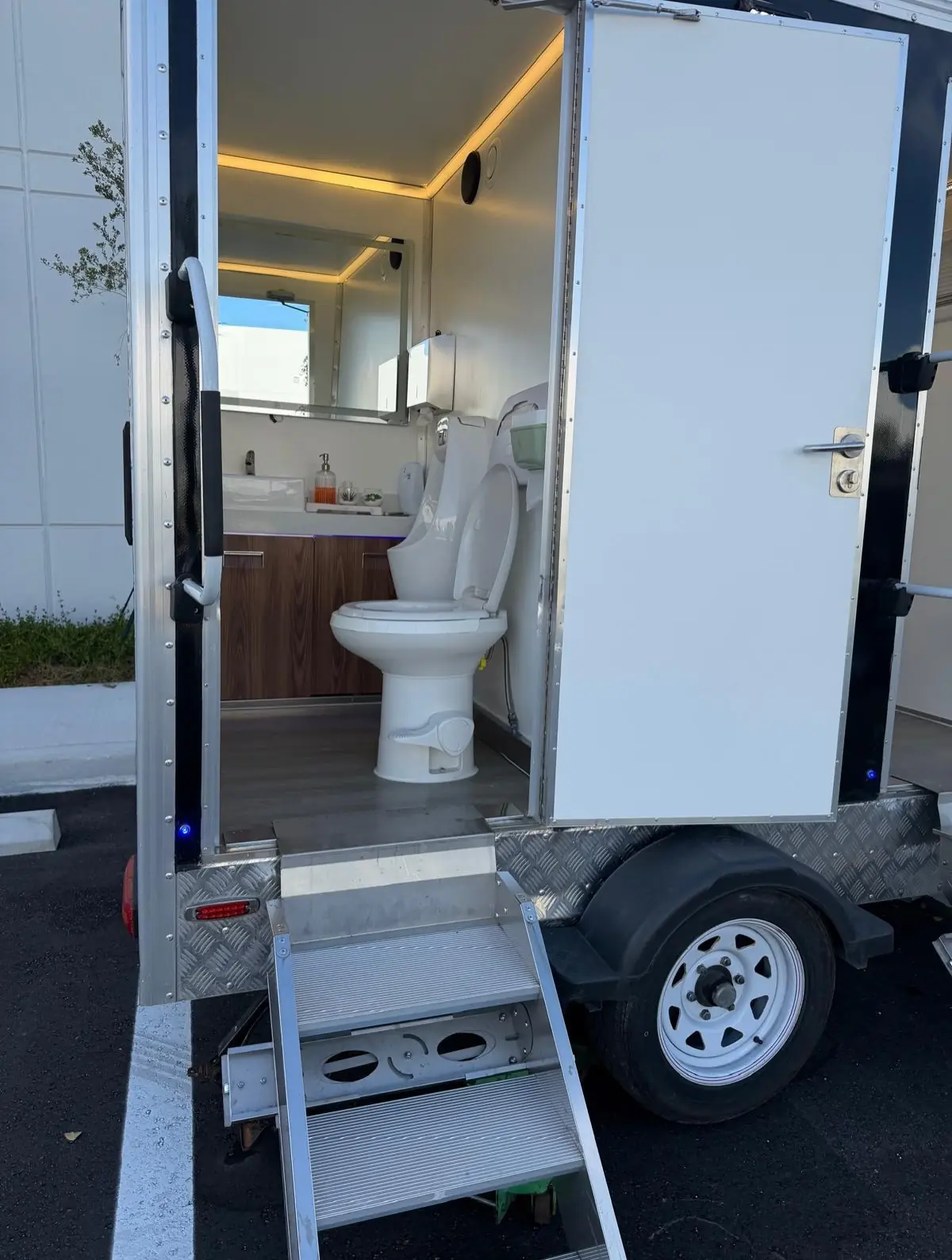 Restroom trailer with lit stalls and fold-down steps