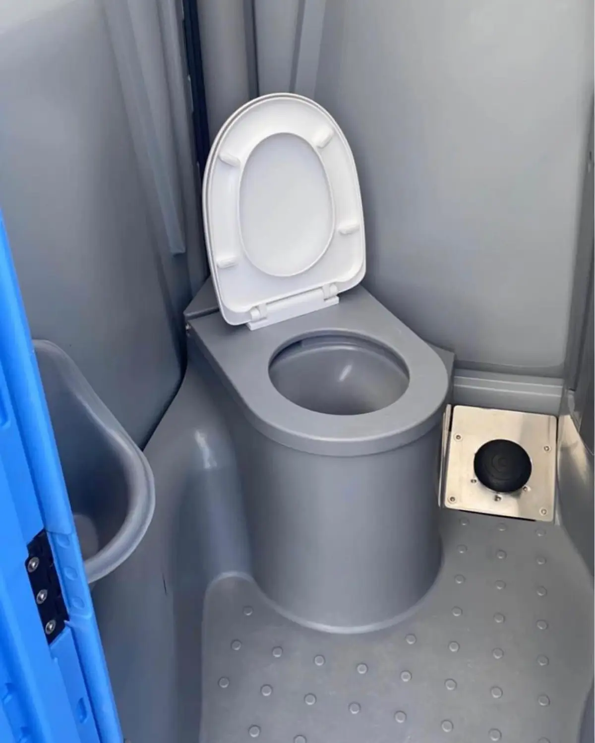 Toilet with a white seat and lid inside a portable restroom