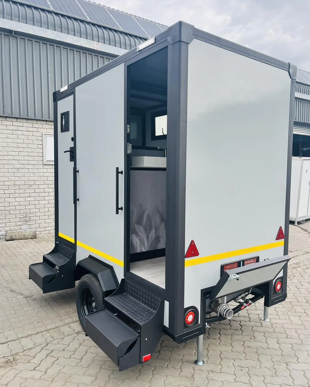 Side view of a compact restroom trailer with fold-down steps
