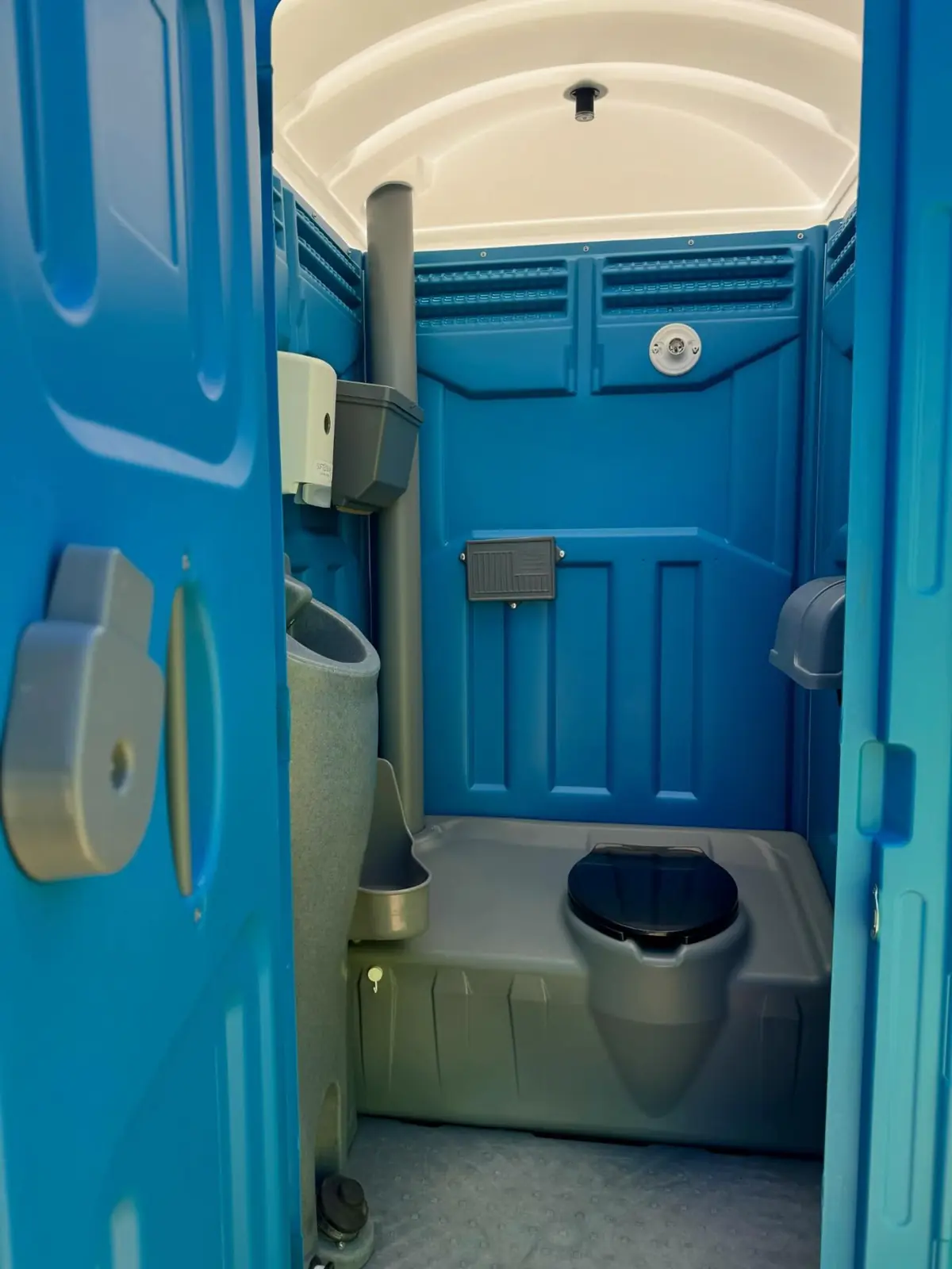 Inside a standard porta potty showing the urinal and seat